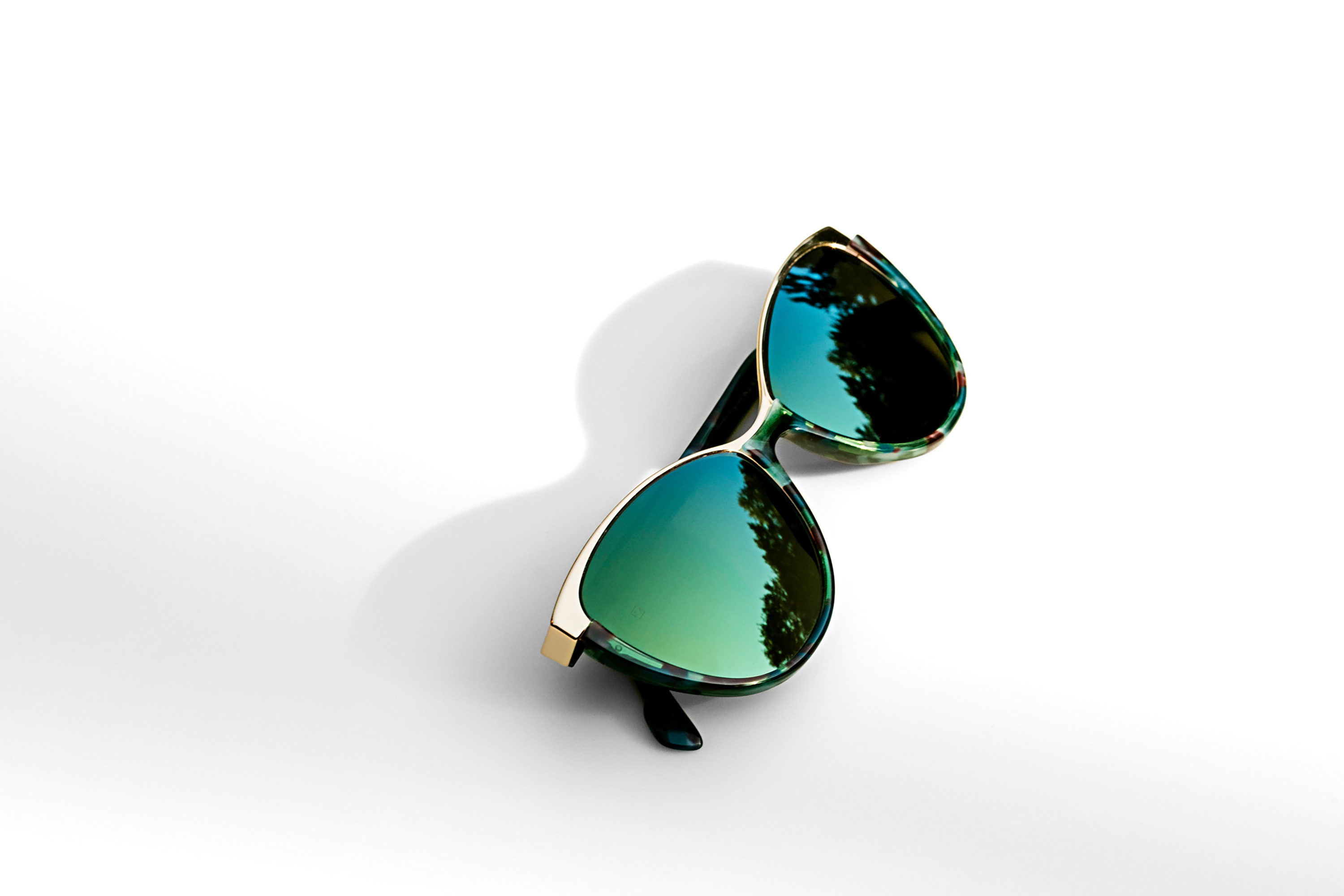 Sunglasses with green mirror-coated lenses photographed on a white background
